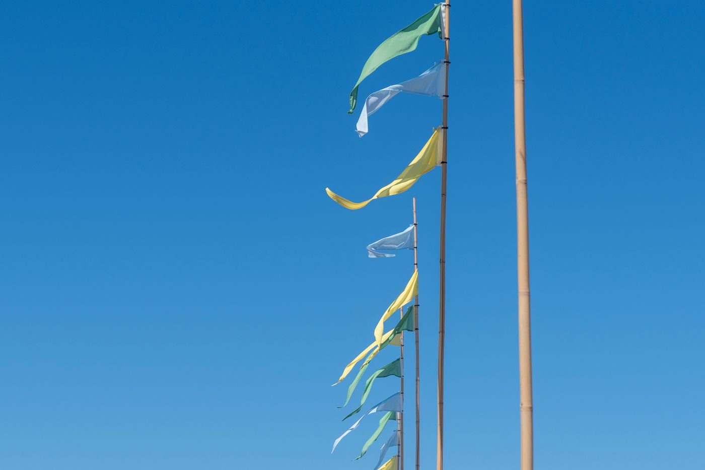 Drapeaux colorés flottant sur des mâts contre un ciel bleu