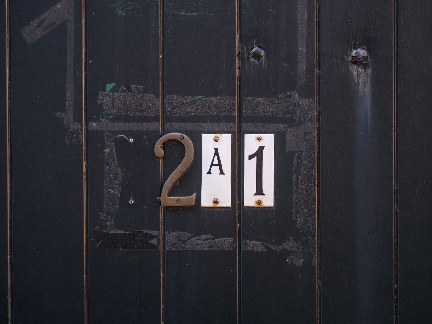 Petites plaques numérotées vissées sur une porte foncée