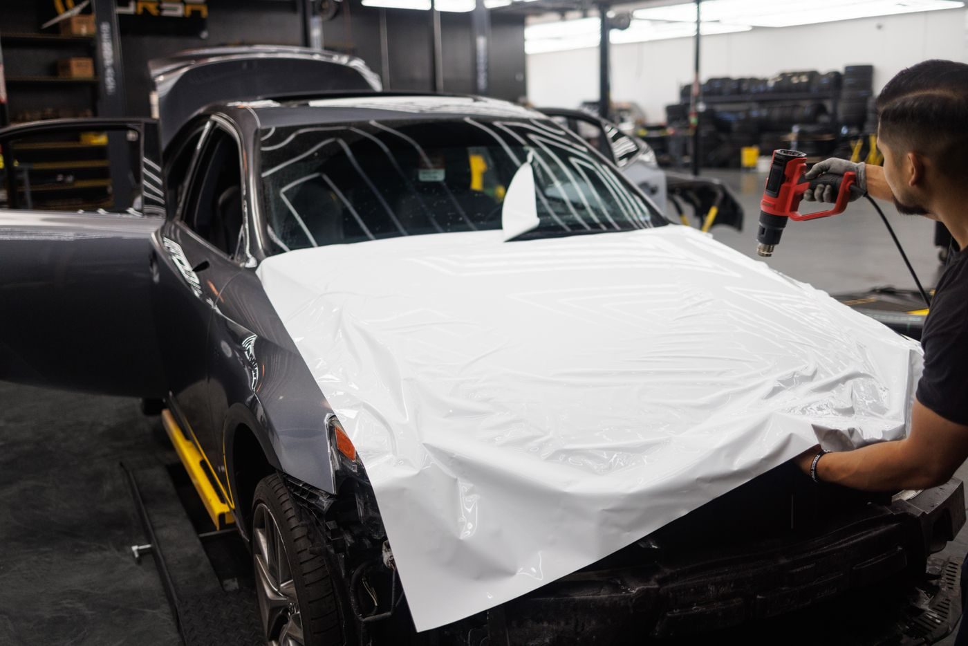Pose d'un film covering sur une voiture en atelier