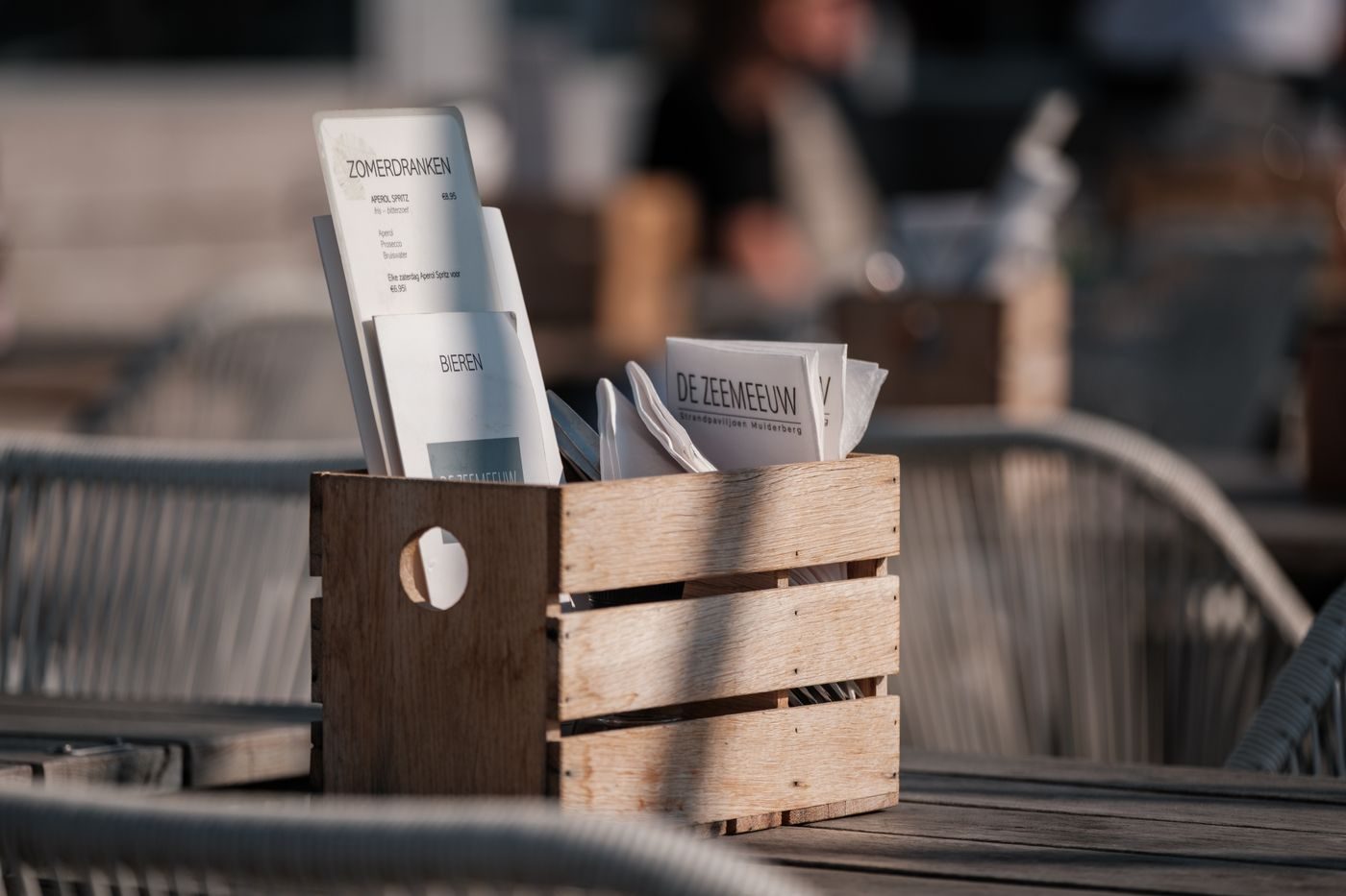 Caisse en bois brut faisant office de porte-menu sur une terrasse
